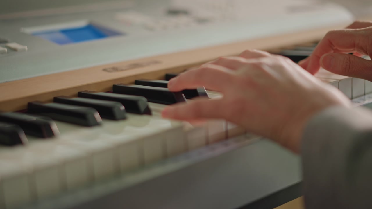 Closeup hands playing keyboard during lesson, piano instructor coaches student through fingering drills on digital keyboard with soft daylight, focused practice on chord changes, rhythm, tone