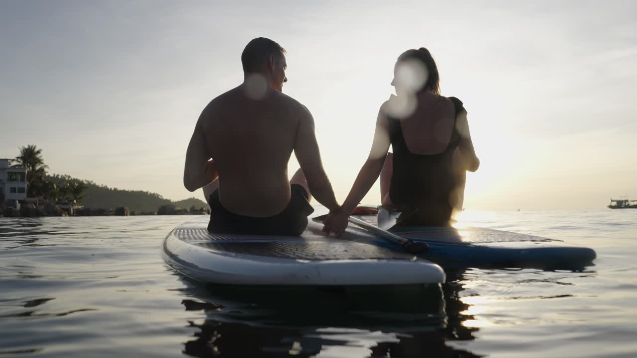 Couple Paddleboarding on the Ocean at Sunset