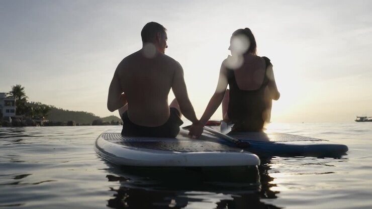 Couple Paddleboarding on the Ocean at Sunset