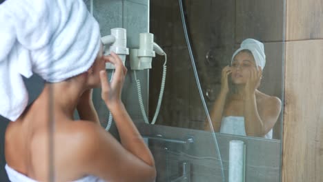 woman applying skincare in a hotel bathroom