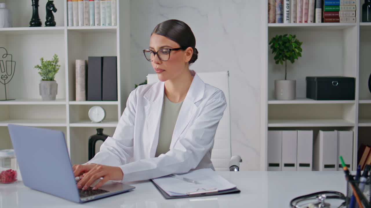 Woman doctor working laptop attentively in modern healthcare clinic closeup