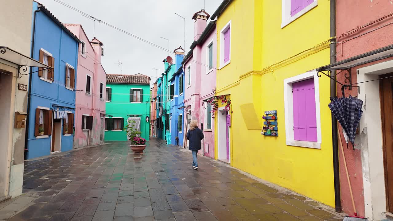 Curious woman Tourist explores colourful painted street houses Burano