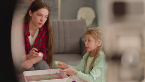 Girl-talks-to-sister-coloring-eggs-for-Easter-at-video-blog