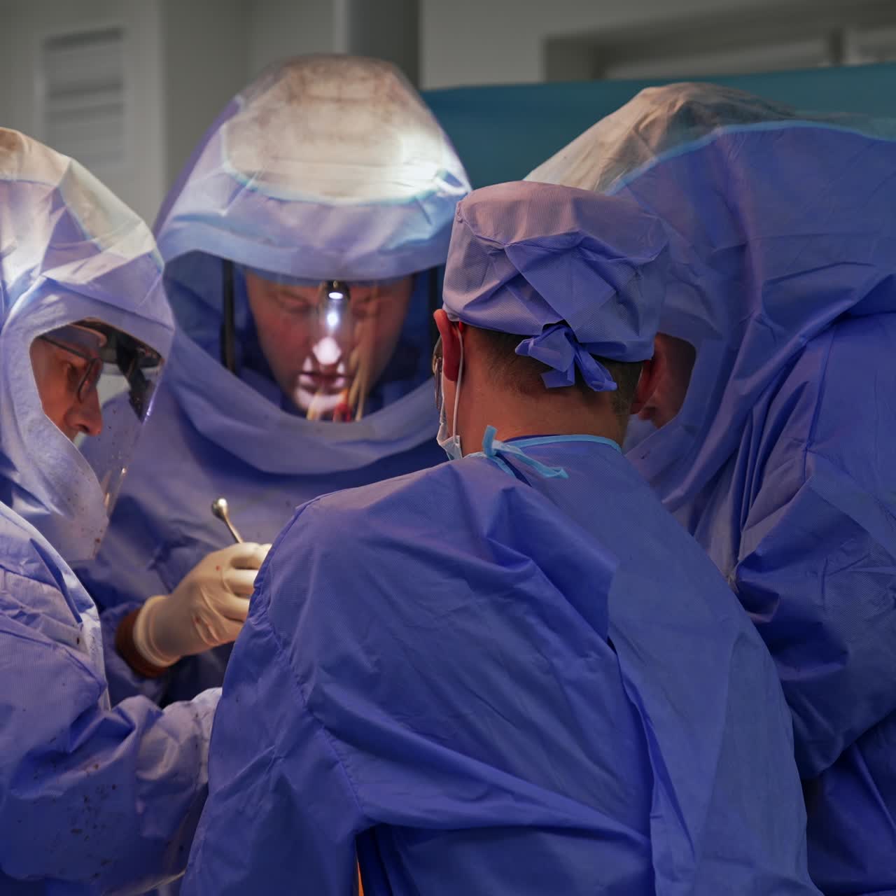 Coordinated work of surgical team in modern operational room. Professional doctors in protective suits cooperate at operation