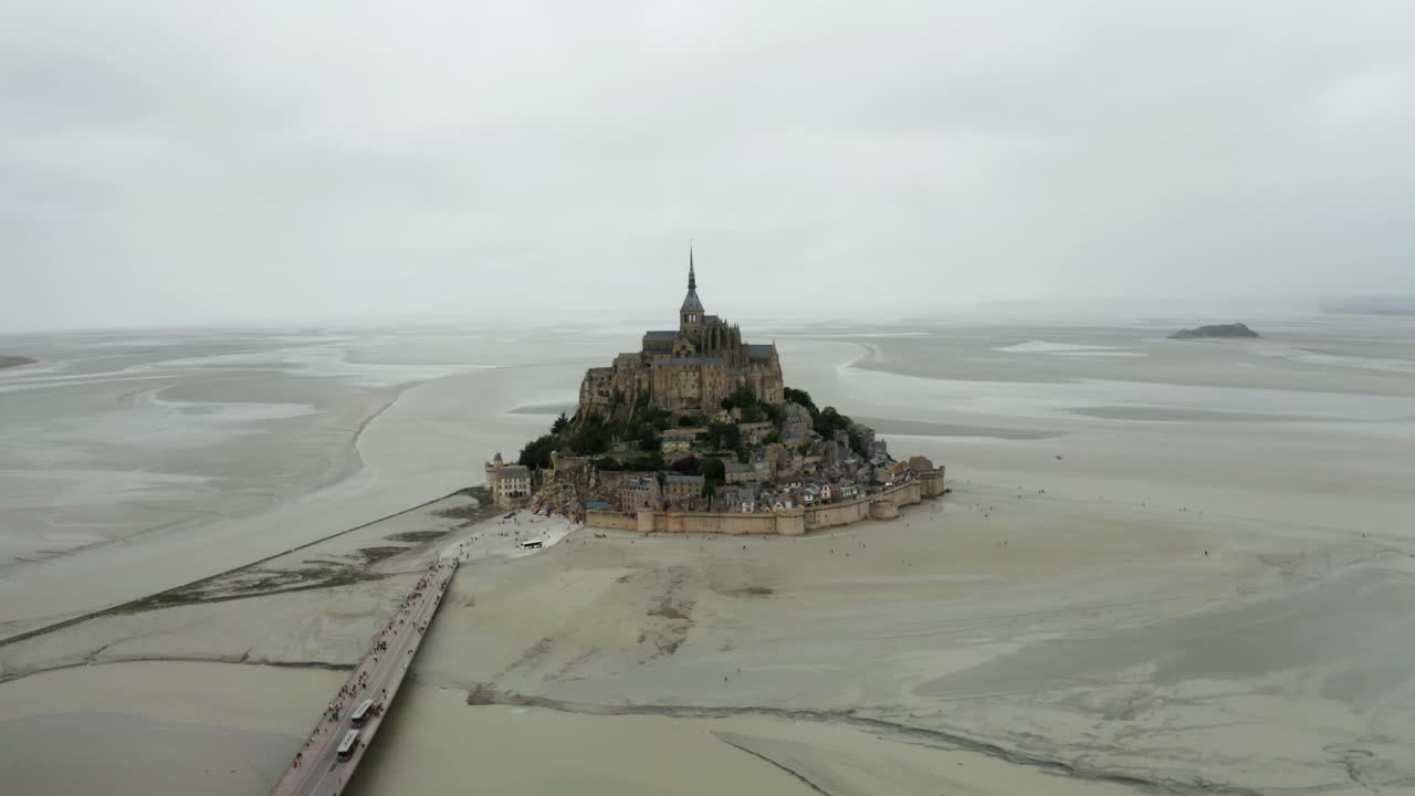 vista aérea de avión no tripulado, mont saint michel cámara no tripulada mirando hacia atrás, hay muchos turistas que regresan después de ver el castillo
