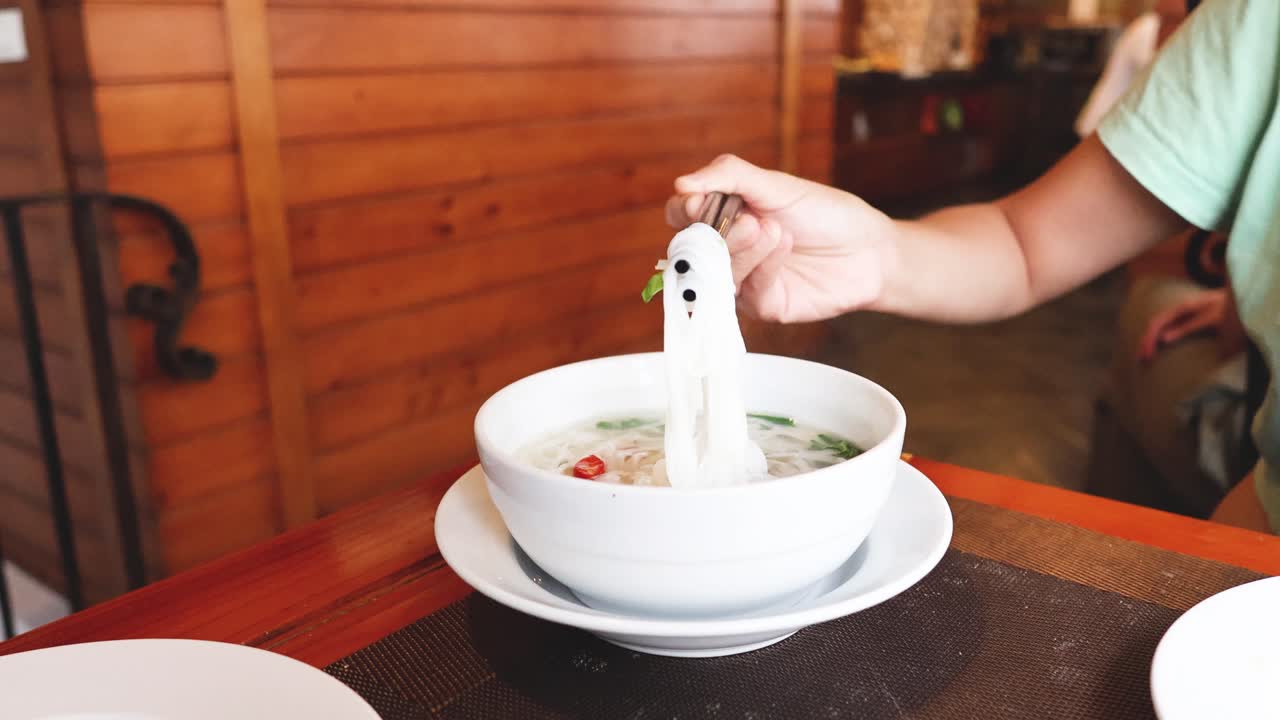 나무 테이블 에서 누들 수프 를 먹는 사람