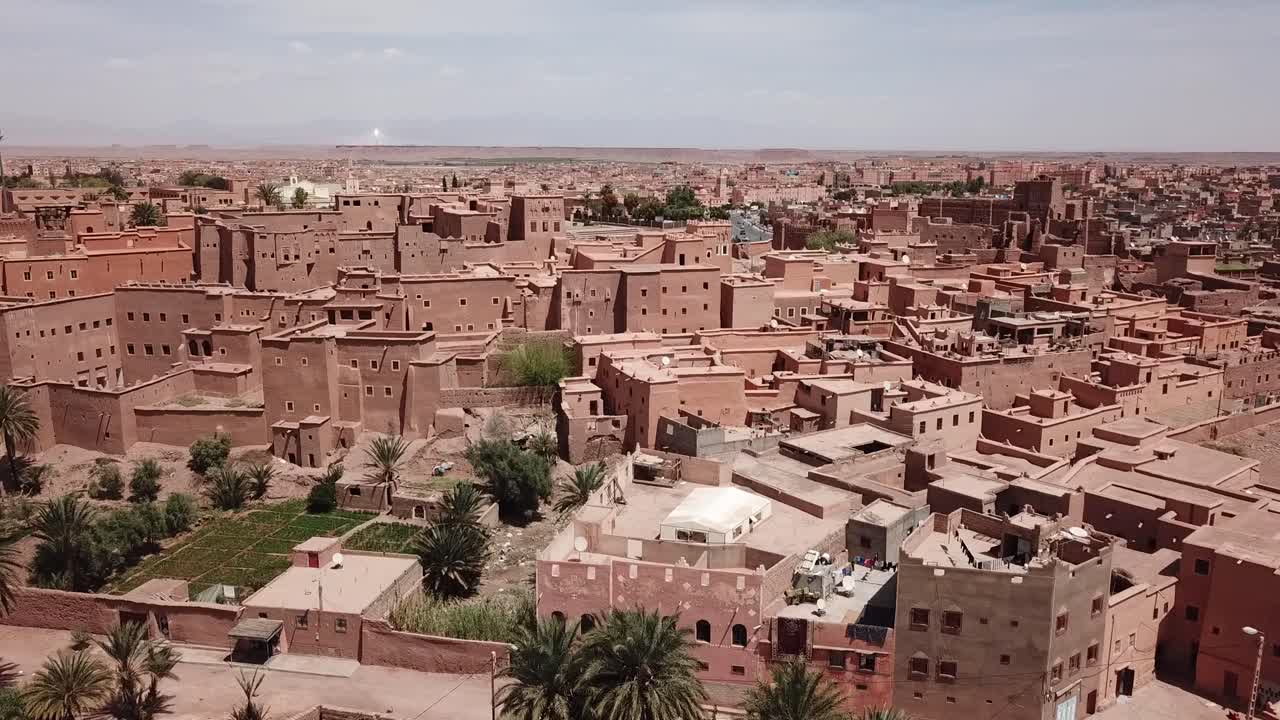 Prospettiva da drone di un villaggio fortificato in mattoni di fango con tetti residenziali e piccoli appezzamenti di giardino nel deserto marocchino