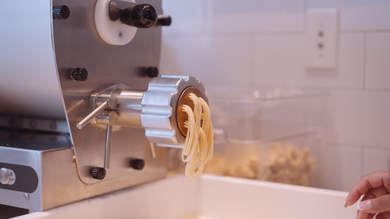 Lunghi fili di spaghetti che escono dalla macchina per la pasta