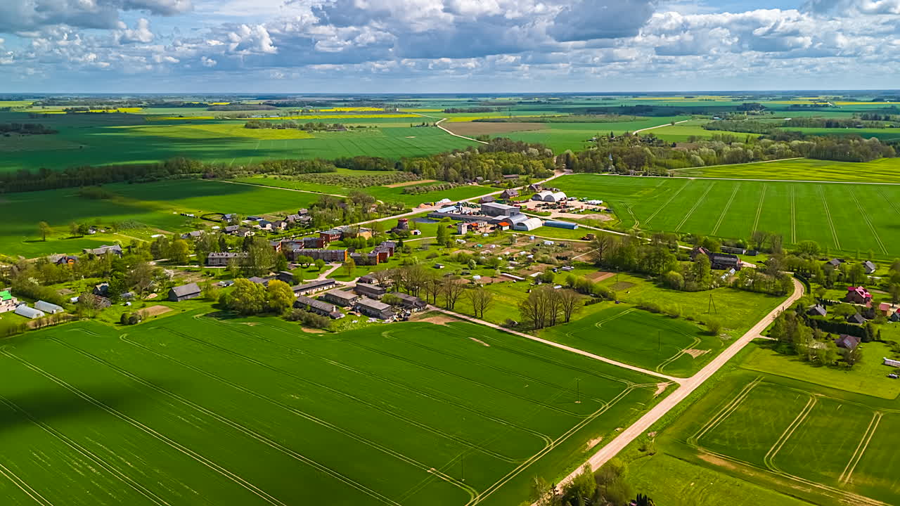 Aerial hyper lapse over countryside farmland fields of crops in Latvia - motion cloudscape time lapse