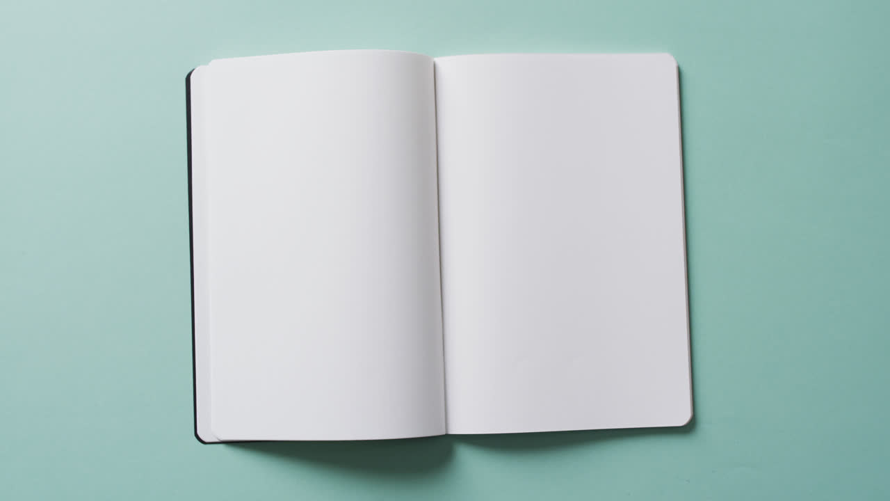 Close up of open blank book with copy space on green background in slow motion