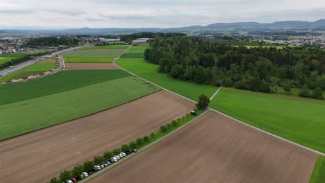 Hünenberg,-Suiza,-Mostrando-Exuberantes-Campos-Verdes,-Tierras-De-Cultivo-Y-Un-Pequeño-Bosque,-Vista-Aérea