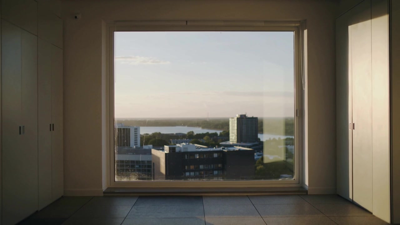 Skiftende sollys gennem et stort vindue kaster skygger på gulvet, skabe i højhuslejlighed mens solen bevæger sig.