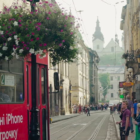 central part of old lviv with pedesrians and red tram going by. beautiful view of architectural buildings and transport in ancient town outdoors.