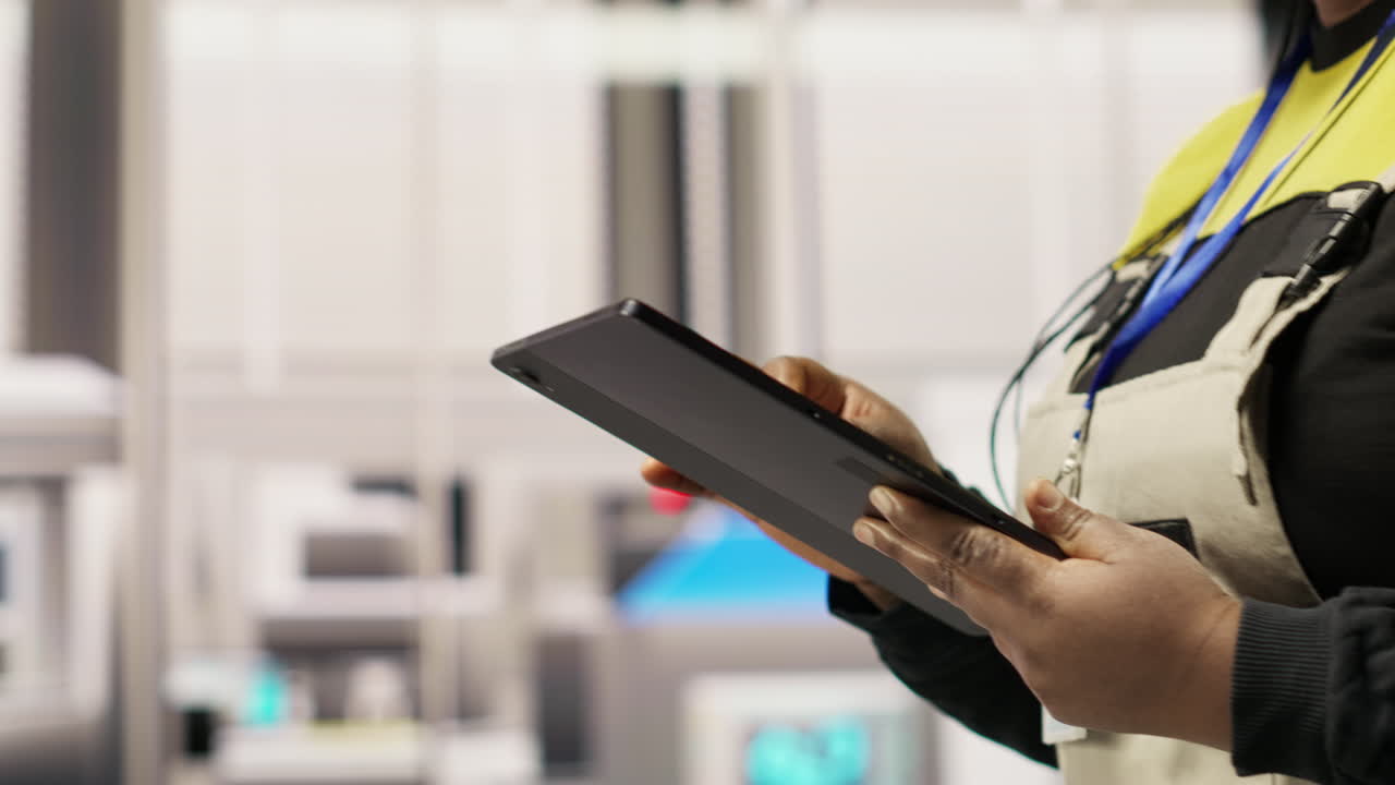 Vertical video Engineer in smart factory oversees robotic assembly lines using tablet app