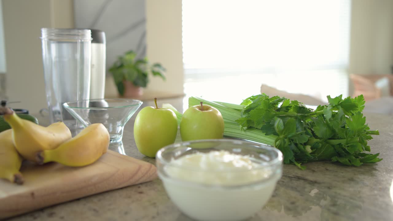 Camera is panning across cutting board on counter, revealing produce and yogurt for smoothie prep