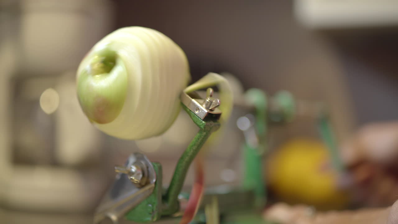 manos de una mujer que operan un pelador manual de manzanas en la cocina