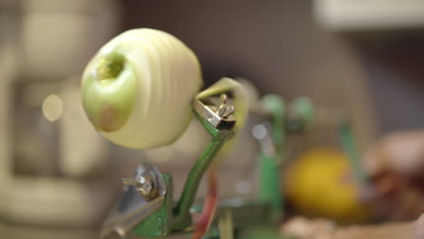 a woman's hands operating a manual apple peeler in the kitchen