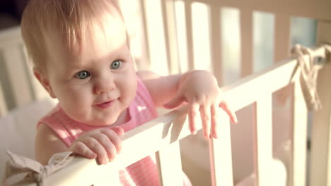 adorable baby reach out hand in cot. little child with interesting face