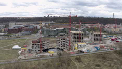 Construction-site-with-tower-cranes-in-Prague-city,-car-traffic-behind