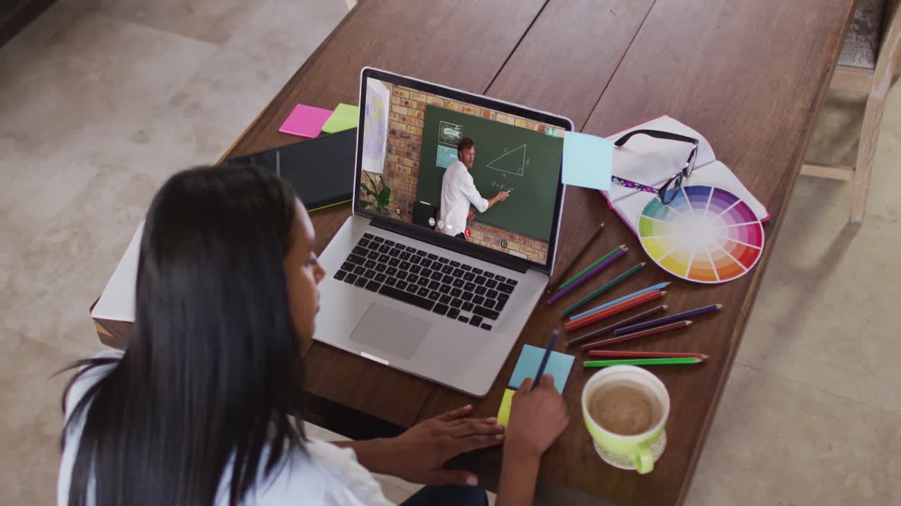 estudiante caucásica usando la computadora en videollamada con un profesor masculino, escribiendo