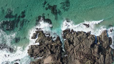 waves crash against the ancient volcanic rock protruding into the warm tropical waters of the pacific ocean