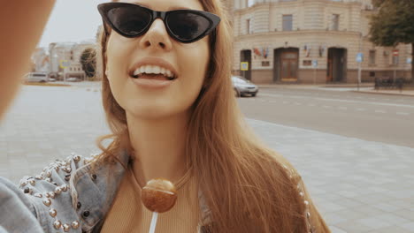 mujer tomando una selfie con una piruleta en una calle de la ciudad