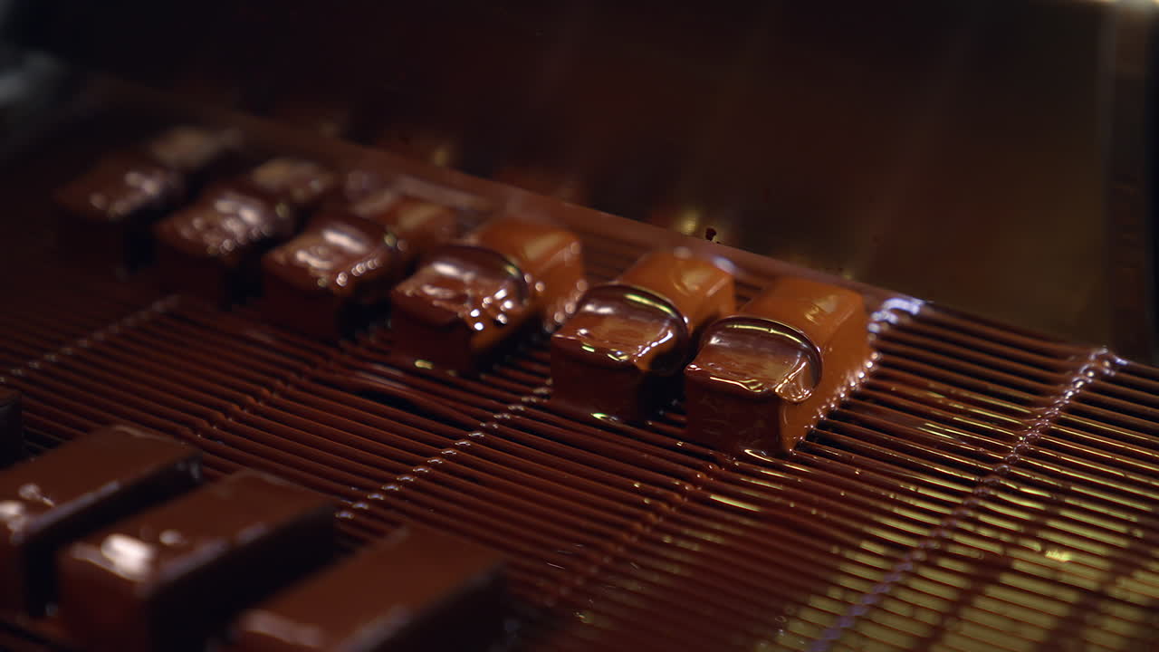 Bars of sweets poured with chocolate. Chocolate bars move along conveyor belt at confectionery factory for the production of sweets.