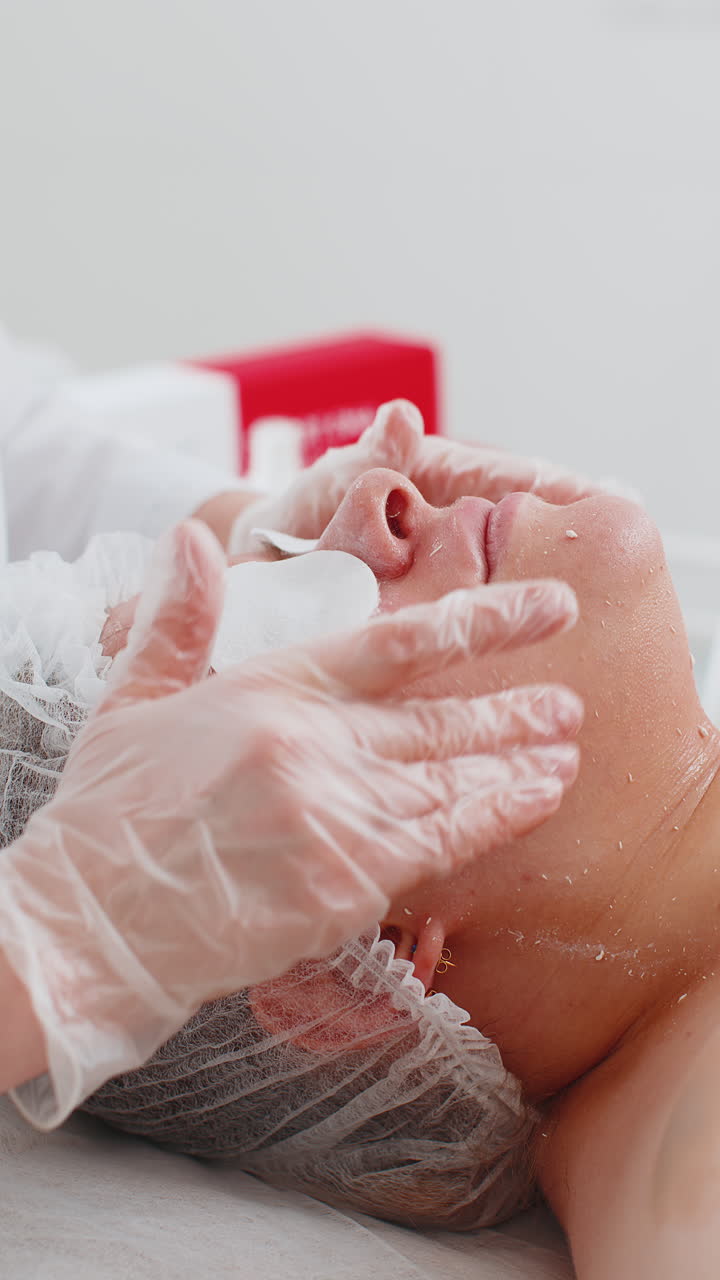 Estetista che applica una crema idratante speciale per il peeling del viso di una graziosa donna caucasica