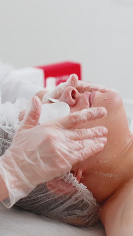 cosmetólogo aplicando crema hidratante especial exfoliando la cara de una bonita mujer caucásica niña