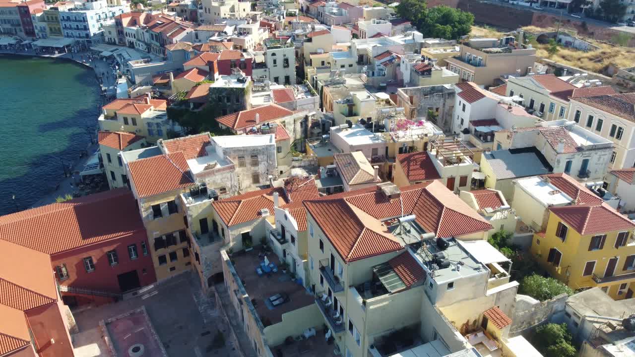 Drone flyover colorful rooftops of Chania's historic center in Crete, Greece on a clear day, textured vibrant mediterranean roof