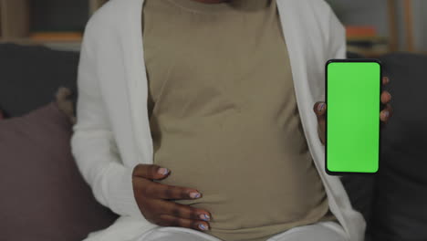 pregnant woman holding phone with green screen