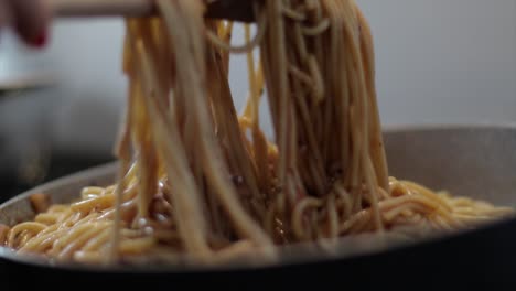 mixing spaghetti with a wooden spoon