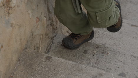 los niños pequeños de primer plano caminan con los pies y los zapatos subiendo escaleras de piedra sosteniendo la vieja pared de escombros