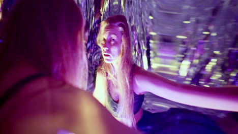woman dancing in front of distorting mirror in vibrant neon lights