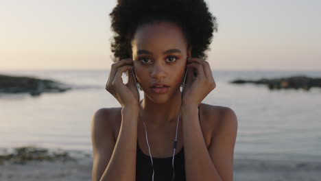 portrait of athletic african american woman looking to camera puts on earphones listening to music