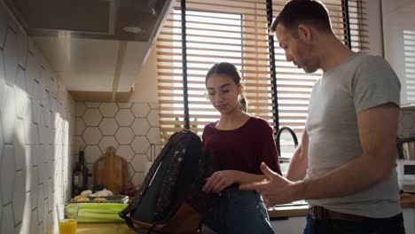 padre caucásico dando una caja de almuerzo a su hija a la escuela
