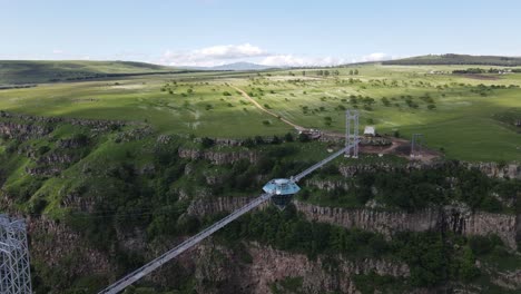 Aerial-shot-of-diamond-bridge-on-top-of-valley-surrounded-by-mountains-green-forest