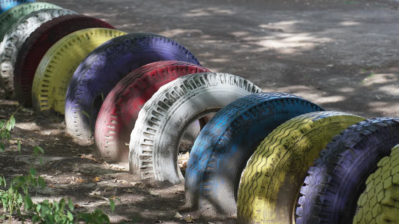 neumáticos pintados de colores dispuestos como decoración de patio de recreo en un parque