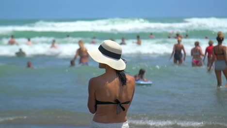 Frau-Mit-Hut-Steht-Am-Strand