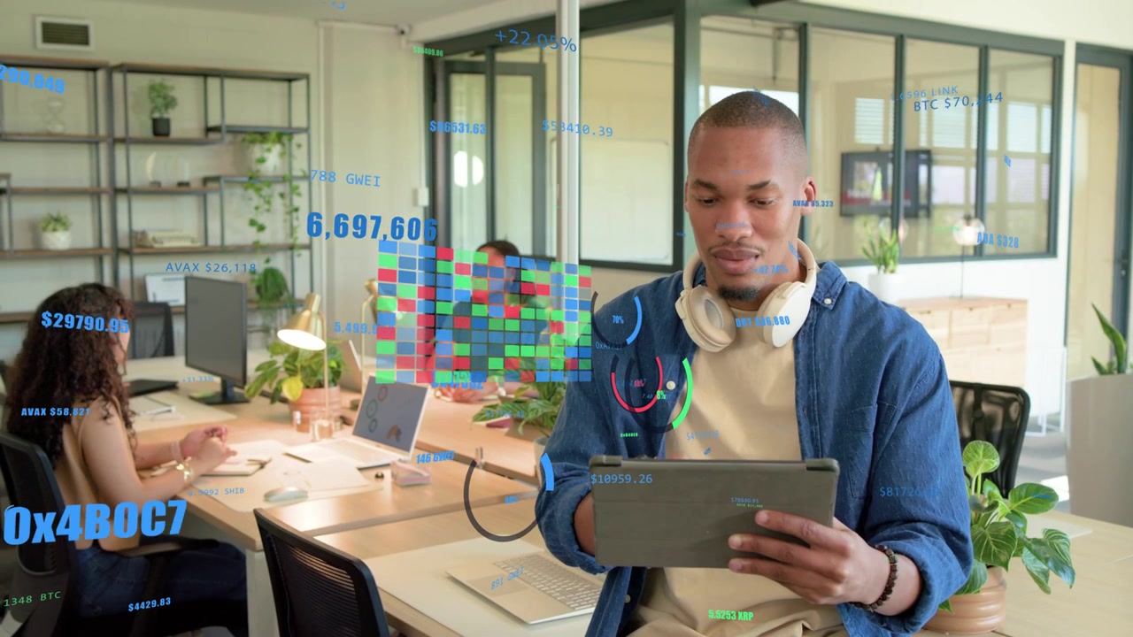 Man sitting on desk edge tapping tablet and showing AR data overlays while analyzing tech metrics