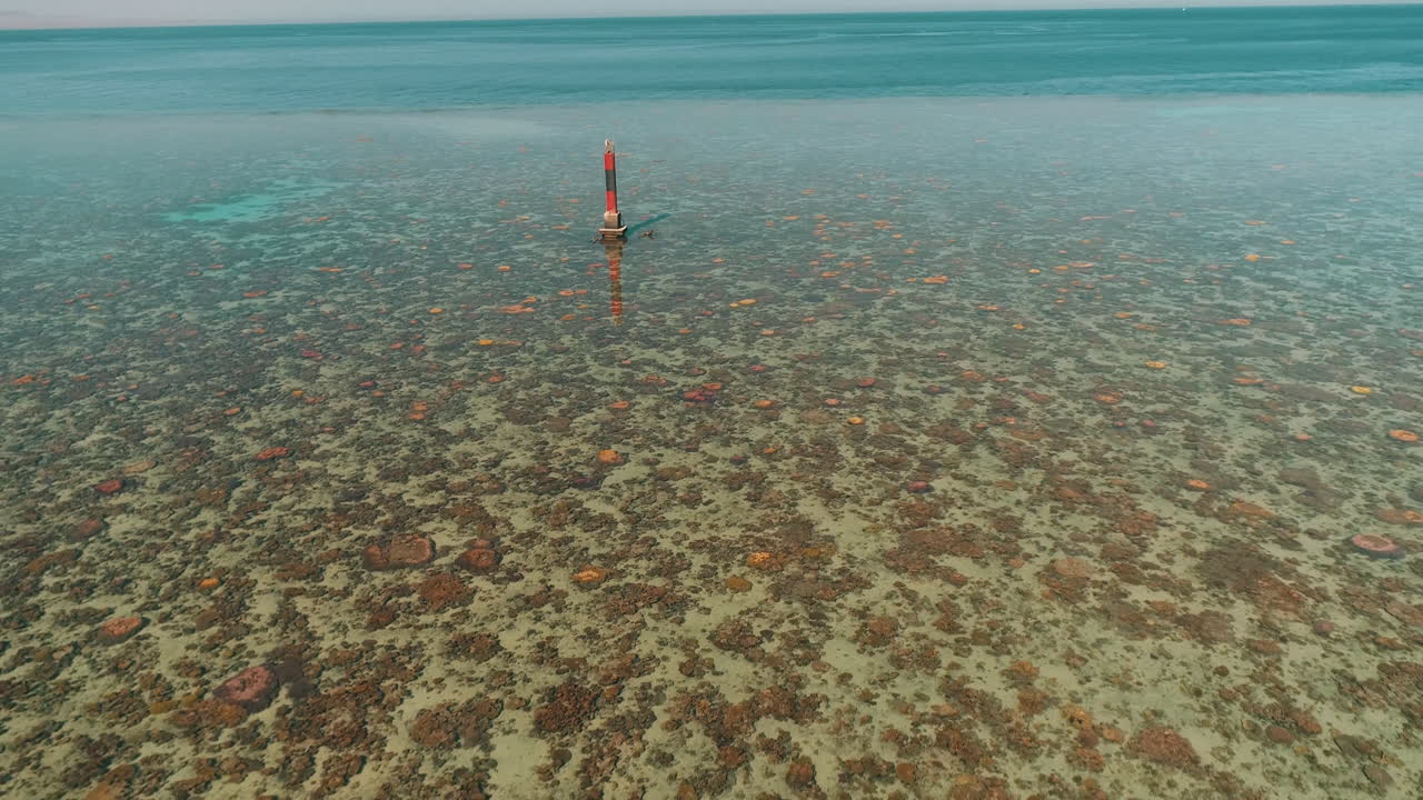 Aerial Shot for the Red Sea of Egypt in the North beside Hurghada with the drone moving backwards from light house on a coral island revealing the wholw site of Abu Nuhas Coral island