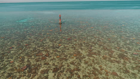 aerial shot for the red sea of egypt in the north beside hurghada with the drone moving backwards from light house on a coral island revealing the wholw site of abu nuhas coral island