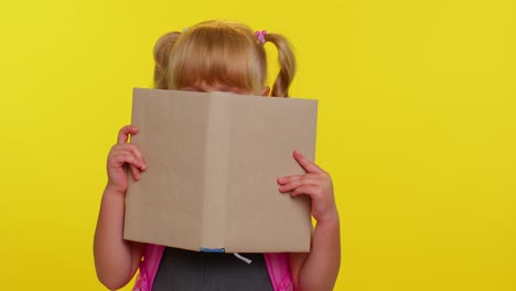 Lovely-teenage-girl-kid-in-school-uniform-wears-pink-backpack-peeping-while-hiding-behind-a-book