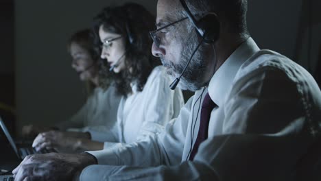 compañeros de trabajo con auriculares escribiendo en portátiles
