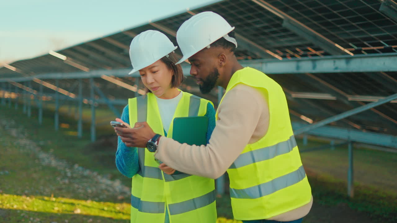 Construction workers inspecting solar panels with a smartphone