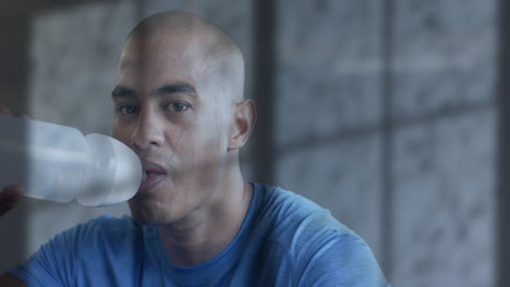 animation of shadow of window over tired biracial man drinking water after exercising