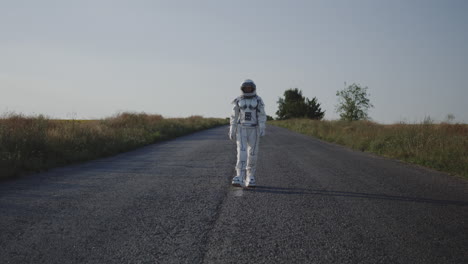 child in astronaut suit walking on a country road