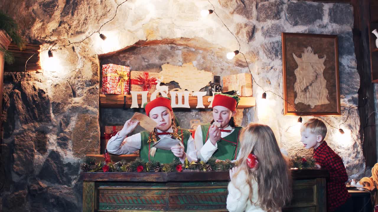 children and elves send a letter to santa claus at the christmas residence