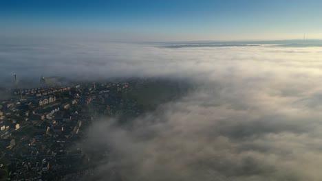 vista aérea cinematográfica de nubes bajas en la mañana de sol de una pequeña ciudad del reino unido
