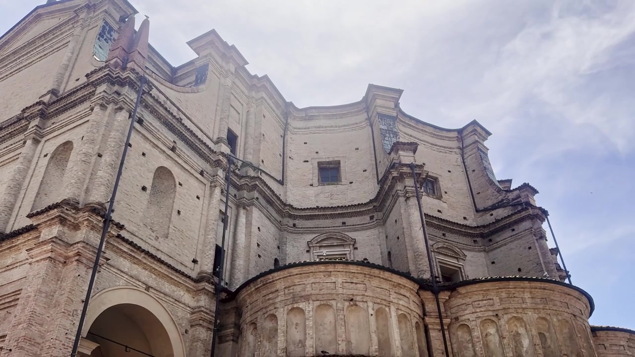Vista dal basso della Santissima Annunziata a Parma, Italia, che rivela il suo esterno in mattoni chiari, le mura rinascimentali curve e i dettagli architettonici ornati